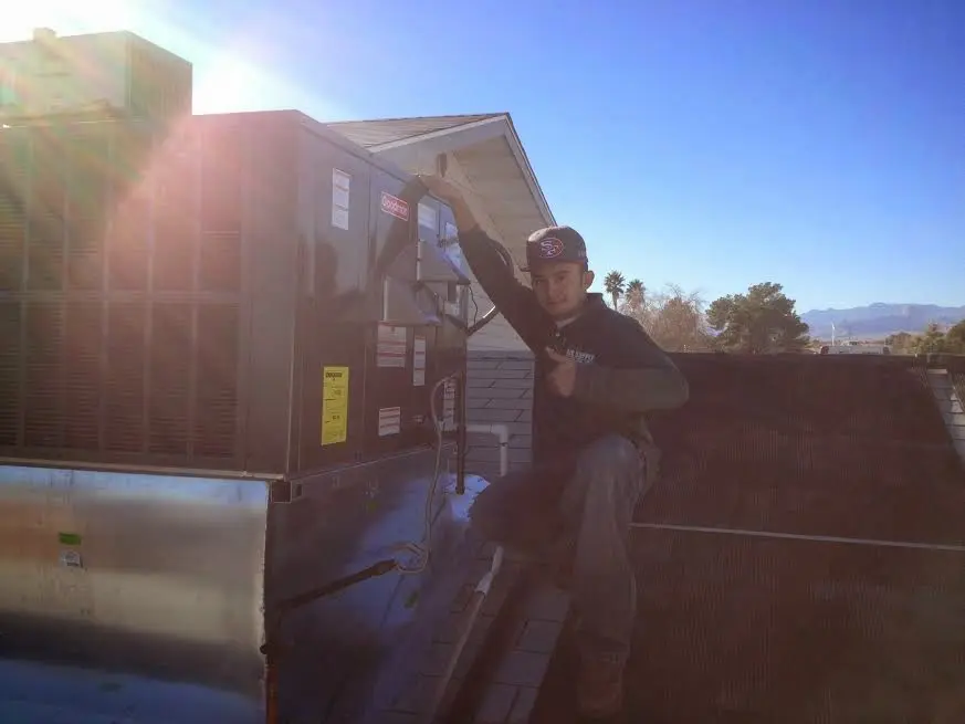 HVAC technician performing AC Tune-Up on a rooftop unit in Moultonborough